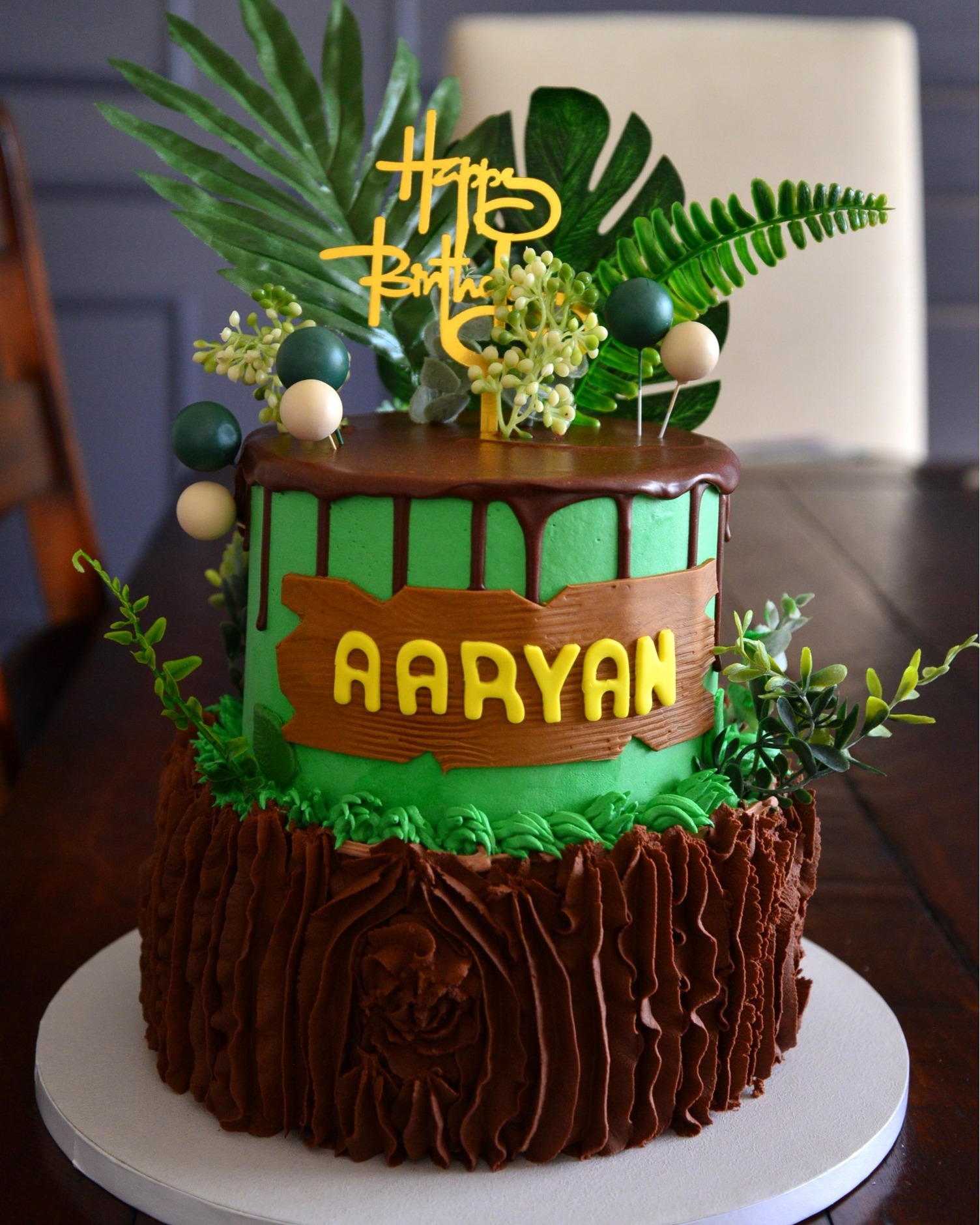 A jungle theme cake with logs design at the bottom, exquisitly jungle theme decorated green cake on the top.